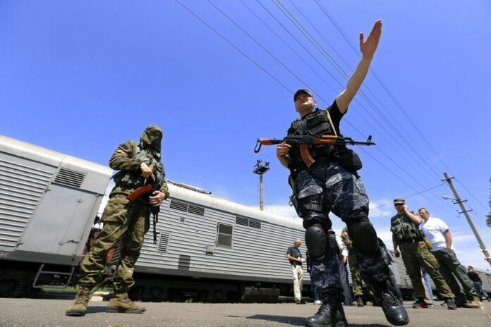 Armed rebels are guarding the train station as OSCE inspectors, in civilian clothes, are waiting for the opening of the train's refrigerated coaches that carry the bodies of the victims of Boeing 777 Malaysia Airlines flight MH17, which crashed during flying over the eastern Ukraine region, at the railway station of Torez, some 90 Km east from Donetsk, Ukraine, 20 July 2014. The MH17 victims' remains are be stored in refrigerated railway coaches and are to be taken to a laboratory in Kharkiv, more than 250 kilometres north of the crash site and far from rebel-held territory. Senior OSCE members were allowed by separatists to check the bodies after being loaded into the refrigerated wagons. A Malaysia Airlines Boeing 777 with more than 280 passengers on board crashed in eastern Ukraine on 17 July. The plane went down between the city of Donetsk and the Russian border, an area that has seen heavy fighting between separatists and Ukrainian government forces. EPA/ROBERT GHEMENT EPA/ROBERT GHEMENT
