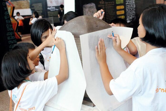 Students copy texts from a replica of the Inscription Stone during an exhibition at Siam Paragon shopping mall, April 2013.