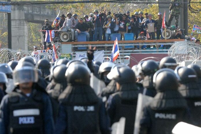 A wounded riot police officer lays on the ground as police came under attacks from anti-government protesters near Phan Fa Bridge in Bangkok, 18 February 2014<br />