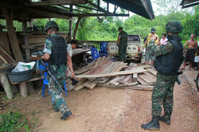 A group of soldiers confiscating illegally harvested logs in Trat province, 5 August 2014. Soldiers have become a common sight in Thailand following the 22 May military coup.