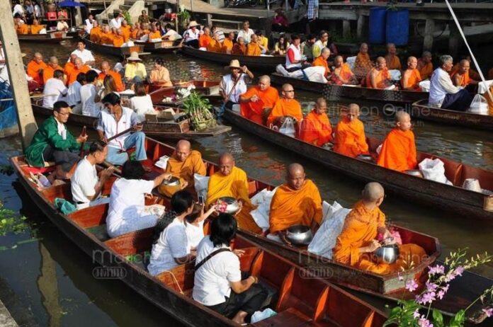 Monks receive alms at Damoen Saduak floating market on 21 November 2010 (Photo by Matichon)