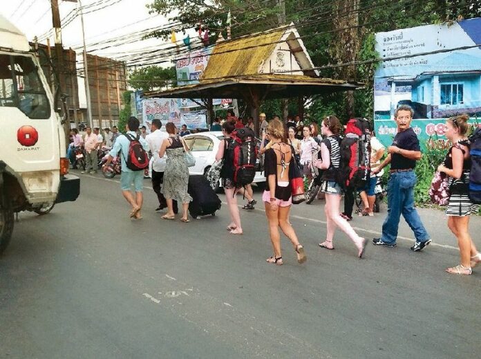 Foreign tourists were forced to walk past a road blockaded by rubber farmers to reach Surat Thani airport on 3 September 2013.<br />