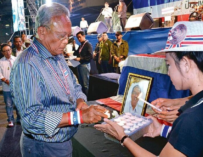 PCAD leader Suthep Thaugsuban lit a candle in front of the coffin of Suthin Tharatin hours after his death on 26 January 2014.<br />