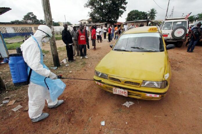 A health care worker disinfecting a taxi in Liberia at an Ebola treatment centre. Photo: WHO/R. Sørensen