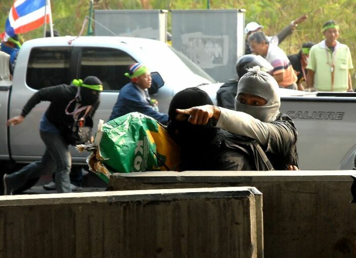 A man wearing a balaclava conceals a rifle in a bag bearing the printed logo of a popcorn company Feb. 1 2014 in Lak Si district.