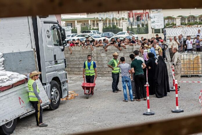 Displaced persons queue up to receive food supplies at a WFP distribution site in the Kasnazan area of Erbil Governorate, in northern Iraq. Photo: OCHA/Iason Athanasiadis<br />