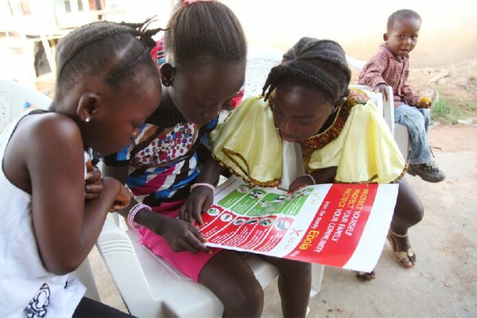 Girls in the city of Voinjama look at a poster that displays information and illustrations about how to prevent the spread of Ebola. Photo: UNICEF/2014/Liberia/Jallanzo