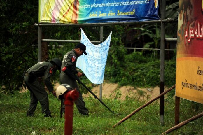 An EOD team looks for bombs near banners in Narathiwat province that police suspect were hung by Islamic separatists in the region, 17 Nov 2014.<br />