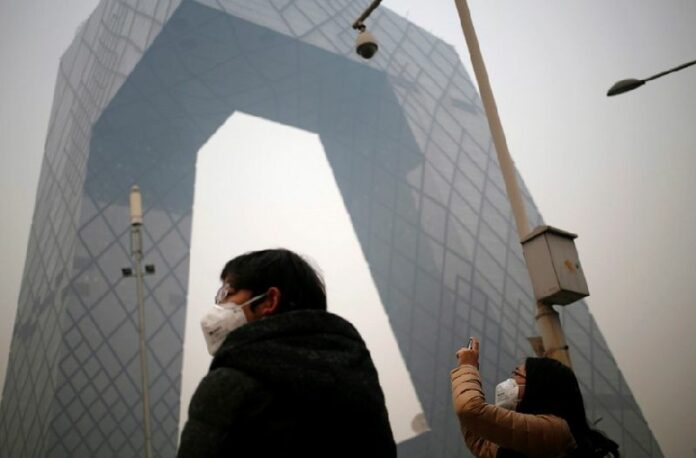 People wearing masks stand in front of the China Central Television (CCTV) Tower shrouded in smog, Beijing, China, on Wednesday. China set a target for coal use on Wednesday, in an effort to curb greenhouse gas emissions in the long-term. EPA/HOW HWEE YOUNG<br />