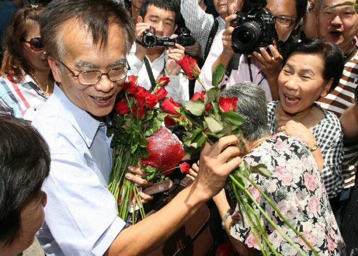 Somsak Jeamteerasakul receives flowers from crowds of supporters after he reported to the police for the lese majeste complaint filed against him by the Thai army, 11 May 2011.