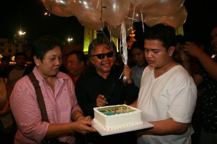Payao (L) and Pansak (C) cut the cake before distributing slices to activists and security officers.<br />