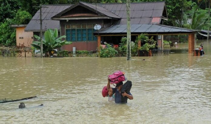 A file photo shows a man and a girl carrying their belongings to safety during a flood in the eastern state of Pahang, 350 km from Kuala Lumpur, Malaysia, 04 December 2013. An 11-year-old boy has gone missing and thousands of people fled their homes as floods hit two north-eastern Malaysian states. EPA/STR MALAYSIA OUT<br />