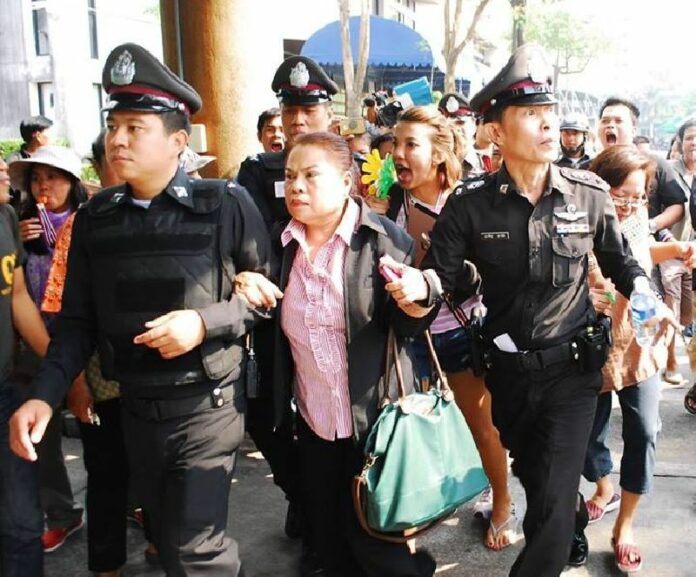 Police officers escort a woman away from a group of anti-government protesters who were besieging a polling station in Bueng Kum district, 26 January 2014