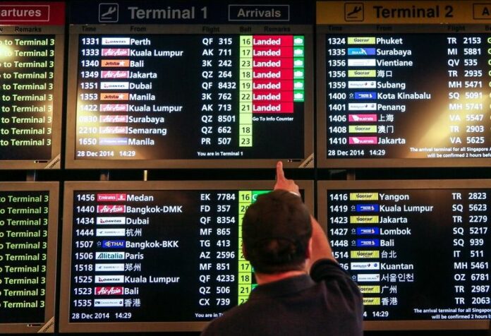 A man pointing at an electronic display showing the arriving flights with the missing AirAsia flight QZ8501 at the Changi Airport in Singapore, 28 December 2014. EPA/WALLACE WOON