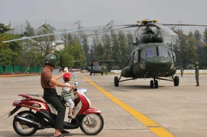 A father shows his child Royal Thai Air Force helicopters that have been transported for the event at National Children's Day at Don Mueang Airport, 8 January 2014.<br />
