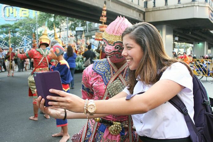 A parade-goer takes a photo a performer in the TAT's "Discover Thainess" parade in Bangkok on 14 Jan 2015.<br />