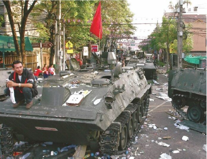 A Redshirt demonstrator sits atop one of armored vehicles left behind by the military after a failed crackdown on the protesters on Ratchadamnern Avenue in Bangkok, 11 April 2010<br />