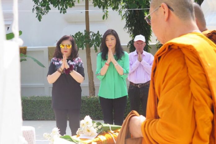 Former PM Yingluck Shinawatra (in green) praying at a temple in Chiang Mai on 10 Feb 2015.<br />