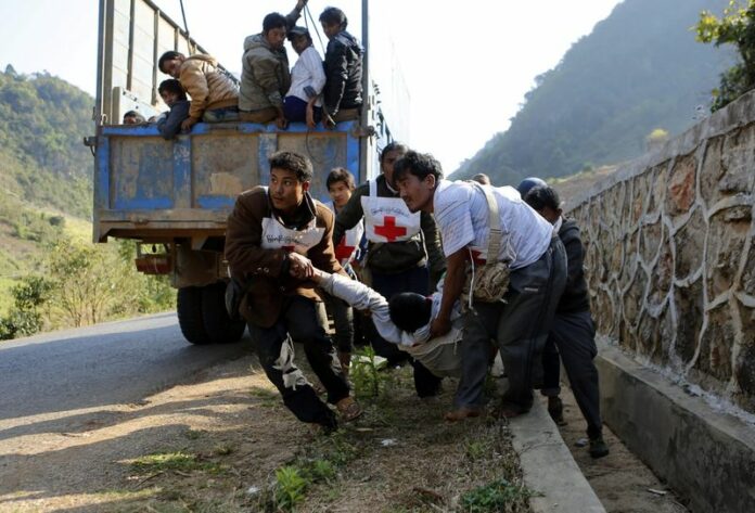 Volunteers of Myanmar's Red Cross organisation carry a wounded volunteer Moe Kyaw, 45, near self-administered Kokang capital Laukkai, northern Shan State, Myanmar, 17 February 2015. EPA/LYNN BO BO<br />