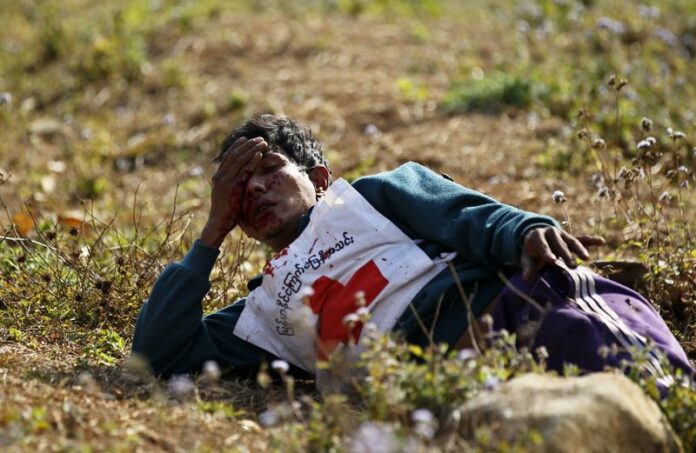 A wounded Red Cross volunteer lies on the ground after vehicles of a rescue convoy were attacked by Kokang rebels near self-administered Kokang capital Laukkai, northern Shan State, Myanmar, 17 February 2015. EPA/LYNN BO BO