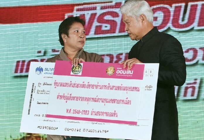 Payao Akhard, mother of a volunteer nurse killed in the 2010 crackdown, receives compensation money from a government representative in a ceremony in Bangkok, 24 May 2012 <br />