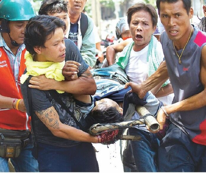 Redshirt demonstrators carry a man who was shot in the head to safety, 15 May 2010.<br />