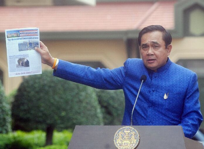 Gen. Prayuth Chan-ocha holding a draft of the gazette at the Government House on 10 March 2015.