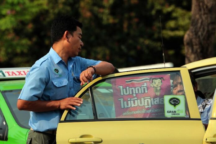 Taxi drivers placed stickers that said "Go Anywhere, No Rejection" on the windows of their cars after taking a pledge in a ceremony organized by the Armed Forces for Maintaining Peace and Order, 13 March 2015.