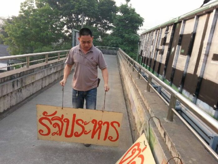 A plain-clothed police officer removing the anti-coup sign in Chiang Mai province, 18 March 2015.