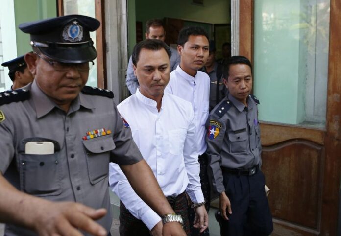 Myanmar citizens Tun Thurein (C-L) and Htut Ko Ko (C-R) are escorted by Myanmar policemen after their hearing at a court in Yangon, Myanmar, 02 January 2015. A court in Myanmar on Tuesday sentenced a New Zealand bar manager and the two Myanmar nationals to two and a half years in prison each, after they used an image of the Buddha wearing headphones in an online promotional poster. EPA/LYNN BO BO<br />