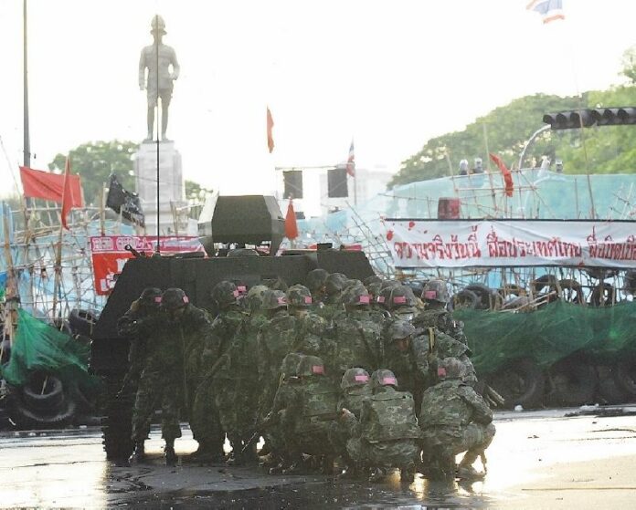 Soldiers take cover behind an armored vehicle as they advance on the Redshirt camp in Bangkok, 19 May 2010. <br />