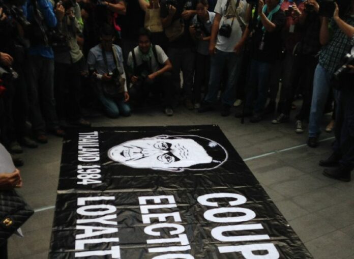 Anti-coup protesters unfurled a banner denouncing Gen. Prayuth as a dictator at a flash protest on 1 June 2014.<br />