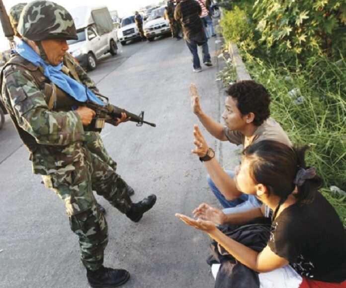A soldier detains two Redshirt protesters at gunpoint following civil unrest in 2010 in Pathum Thani province.