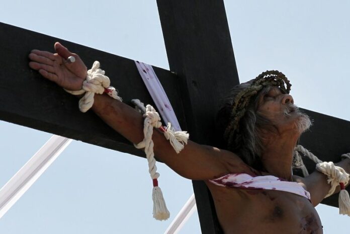 A Filipino penitent is nailed to a wooden cross during the re-enactment of the crucifixion of Jesus Christ on Good Friday, in San Juan village, San Fernando city, north of Manila, Philippines, 03 April 2015. Every year, thousands of foreign and local visitors flock to San Pedro Cutud village, San Fernando city, to watch hooded and barefoot penitents lash their backs bloody along a narrow road that leads to a dusty hillock, where other men dressed as Jesus Christ are nailed to wooden crosses. EPA/RITCHIE B. TONGO<br />