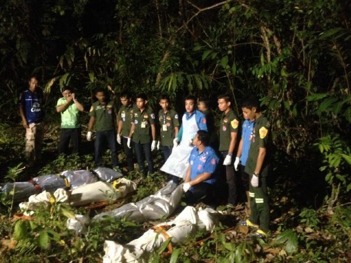 Rescue workers stand behind the corpses of the four men killed in the raid in To Chud Village, Pattani province, 25 March 2015.