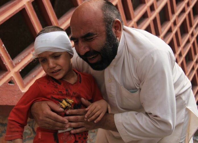 An Afghan man holds his son, who was injured in a suicide bomb attack, outside a local hospital in Jalalabad, Afghanistan, on April 18. Islamic State militants have claimed responsibility.