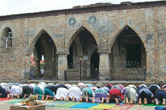 Muslims pray in front of the ruins of Krue Se mosque, 30 April 2004
