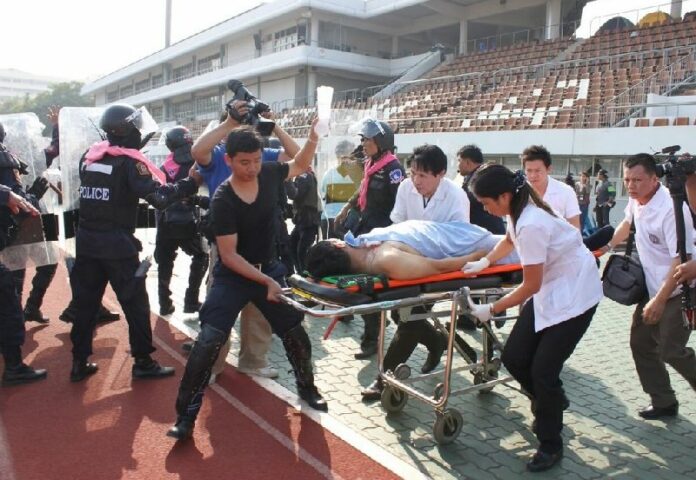 Rescue workers evacuate an injured police officer from clashes at Thai - Japan Stadium in Bangkok, 26 December 2013