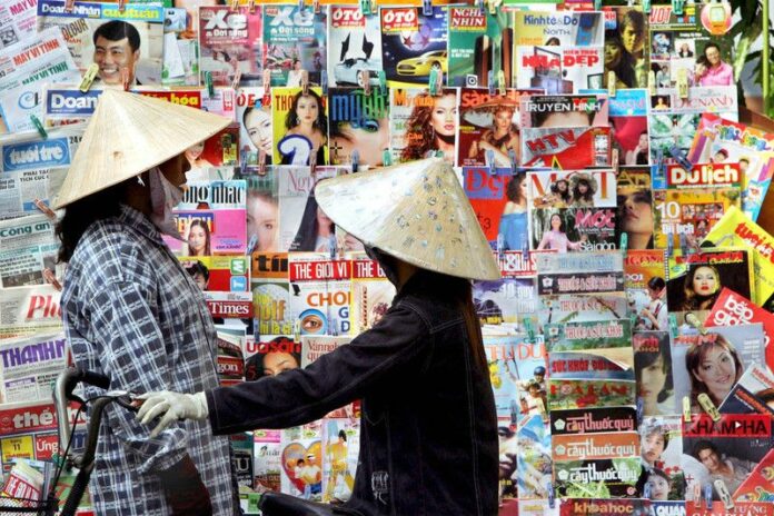 Two Vietnamese street vendors chat in front of a magazine stand as they wait for costumers in a busy street in Ho Chi Minh City in Vietnam on Tuesday, 26 April 2005. A Vietnamese magazine editor was charged with crimes against the state for publishing articles accusing senior officials of corruption. EPA/MAST IRHAM<br />
