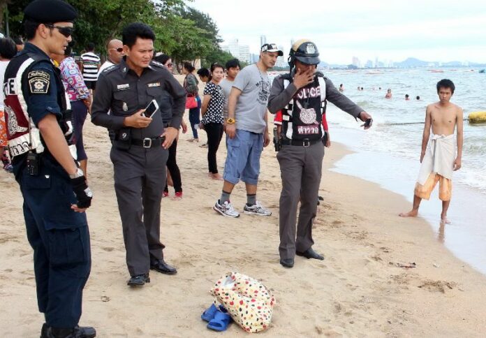 Police inspect the scene on Jomtien beach where a 76-year-old woman was found dead on 20 May 2015.