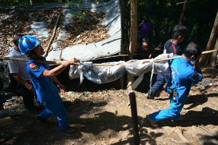 Thai rescue workers carry a dead body from the suspected detention camp in Songkhla province on 1 May 2015.<br />