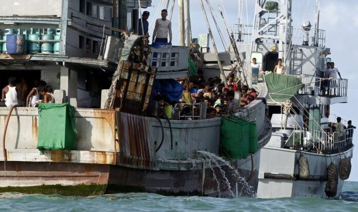 A Myanmar Navy vessel tugs a boat of migrants near Thameehla island, Irrawaddy division, Myanmar. EPA/STR<br />