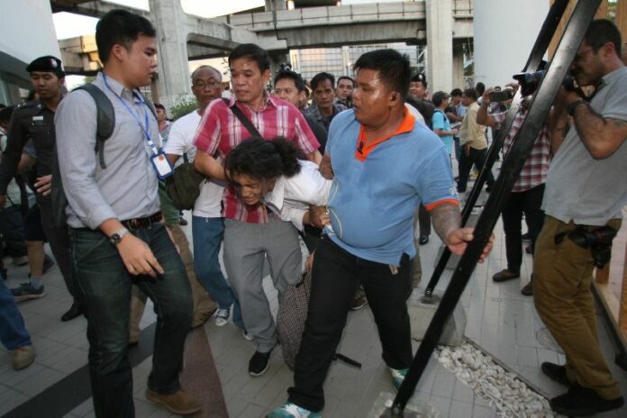 Security officers drag protesters away from an anti-coup demonstration in downtown Bangkok on 22 May 2015.