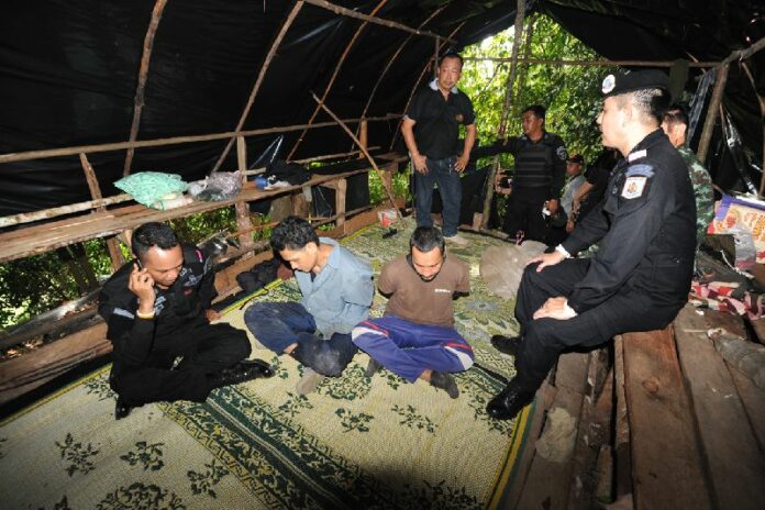 Two suspected insurgents are detained by security officers at a jungle outpost in Narathiwat province, 12 June 2015.