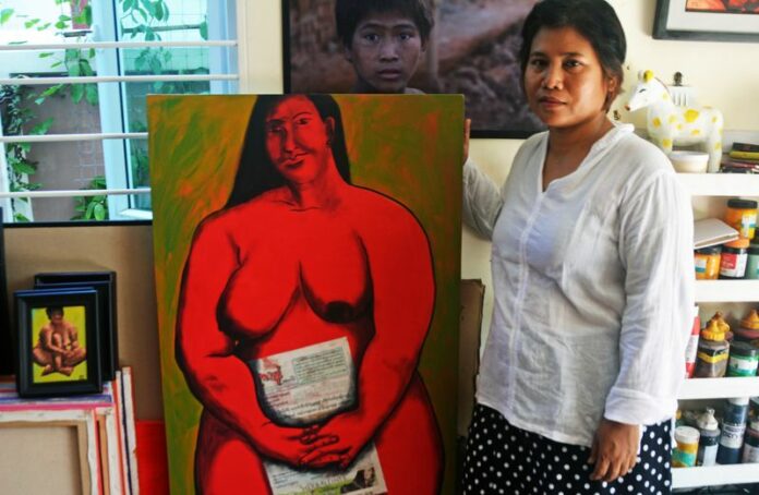 The artist Sandar Khine poses with a recent painting in her studio, Yangon, Myanmar, May 2015. Photo: Paul Vrieze/dpa<br />
