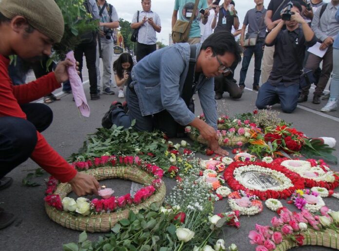 Activists lay flowers around a plaque that marks the spot where a leader of the 1932 coup proclaimed the beginning of democracy in Thailand, 24 June 2015.