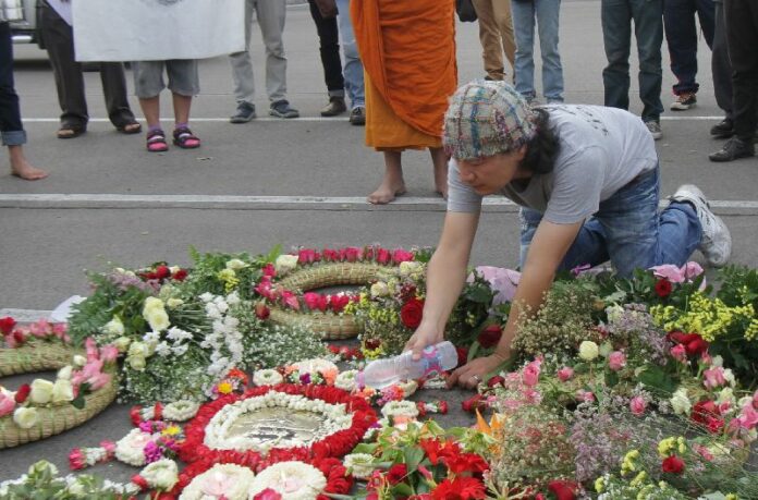 Activists lay flowers around a plaque that marks the spot where a leader of the 1932 coup proclaimed the beginning of democracy in Thailand, 24 June 2015.