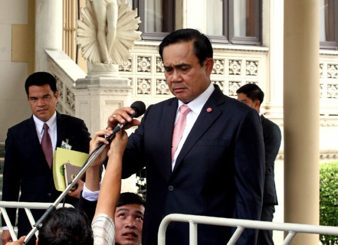 A journalist helps adjust Gen. Prayuth Chan-ocha's microphone during a press conference at the Government House, 25 June 2015.