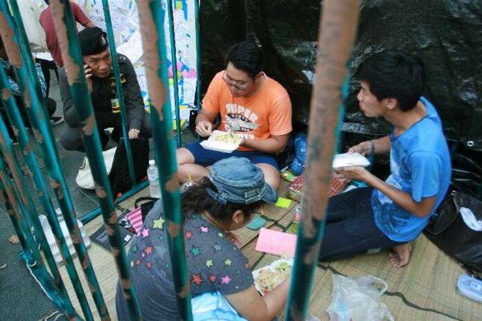 Students sit in a mock prison in front of Thammasat University to show solidarity with jailed pro-democracy activists, 1 July 2015.<br />