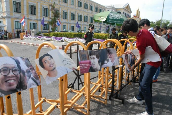 Supporters of the 14 jailed activists hang their portraits along a barricade outside of Bangkok's martial court, 7 July 2015.